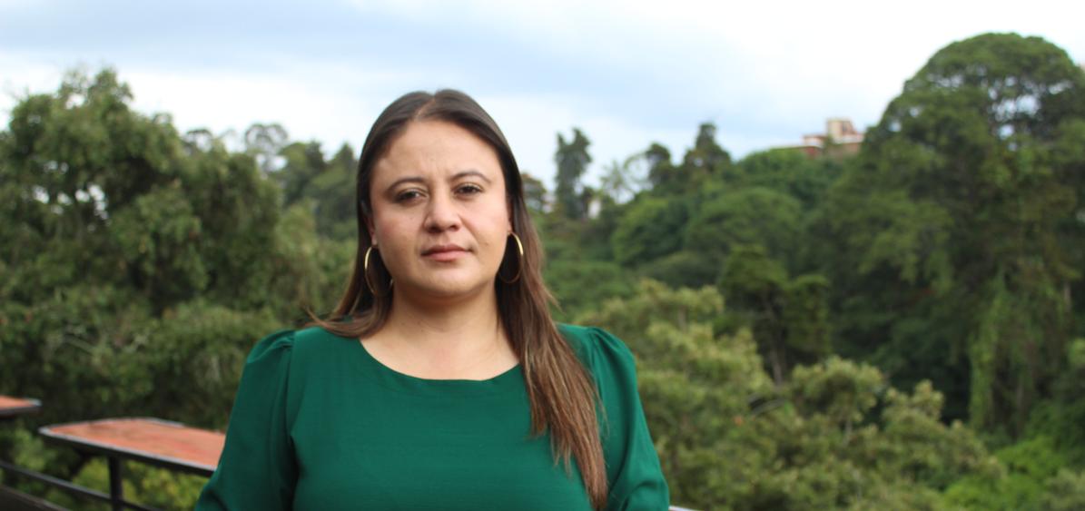 La exfiscal de la Fiscalía Especial contra la Impunidad (FECI), Paola Pimentel viste una camisa de manga larga verde mientras se encuentra al aire libre, rodeada por un paisaje de montañas.
